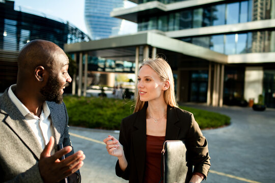 Two business professionals discussing project outside modern office