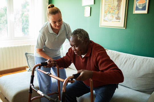 Caregiver helping senior man with walker at home