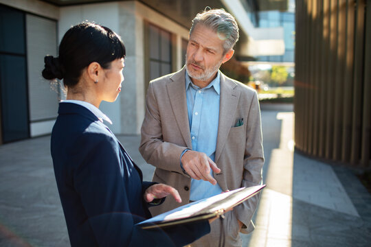 Senior manager and colleague reviewing report outside office