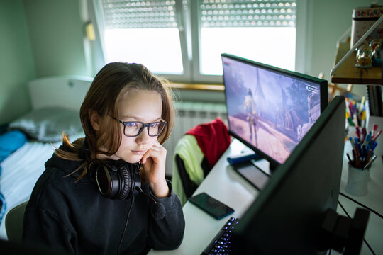 Teen gamer with headset playing pc game at home bedroom desk