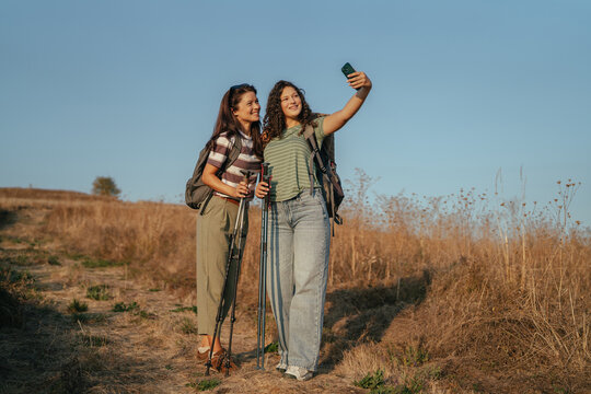 Women friends hiking taking selfie on trail