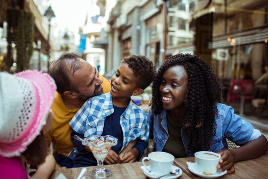 Smiling family with kids enjoying dessert at outdoor cafe