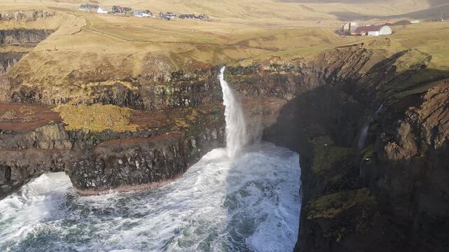 フェロー諸島の断崖から海へ落ちる滝と草原の小さな集落を空撮（Faroe Islands Cliff Waterfall Aerial 4K）