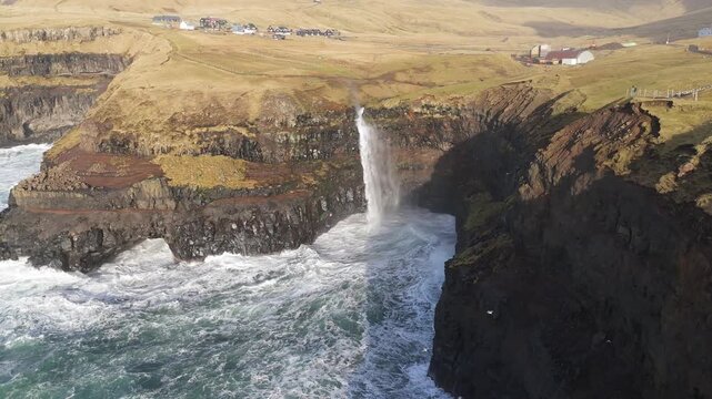 フェロー諸島ガーサダルルのムーラフォッスル滝と断崖に砕ける荒波の空撮（Mulafossur Waterfall, Gasadalur, Faroe Islands Aerial 4K）