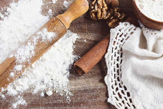 Preparing organic baking ingredients with a rolling pin, flour, and walnuts on a rustic wooden surface, highlighting the process of homemade food preparation and healthy cooking concepts.