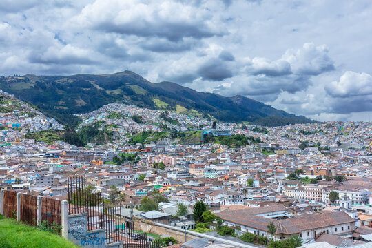 Colorful colorful houses and dense residential buildings built on the hillside slopes in Quito, Ecuador, against Andean mountain background.