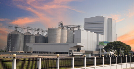 Exterior view of a large-scale animal feed mill plant or grain terminal.Large industrial grain silo complex and food processing factory building. © Rangsarit