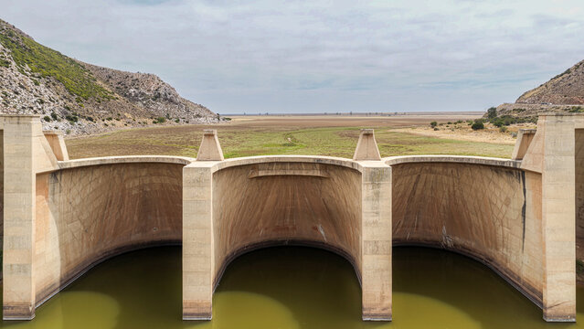 Aerial view of the concrete dam structure in the Little Karoo, surrounded by arid plains and dry landscape in Garden Route District Municipality, Western Cape, South Africa.