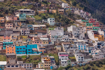Fototapeta premium Colorful colorful houses and dense residential buildings built on the hillside slopes in Quito, Ecuador, against Andean mountain background.