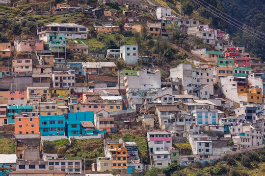 Colorful colorful houses and dense residential buildings built on the hillside slopes in Quito, Ecuador, against Andean mountain background.