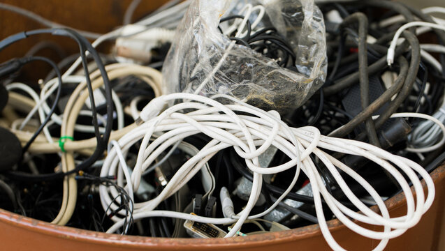 Tangled pile of old computer and electrical cables stored in a box, illustrating electronic waste, obsolete technology, cable clutter, recycling, overconsumption and storage problems.