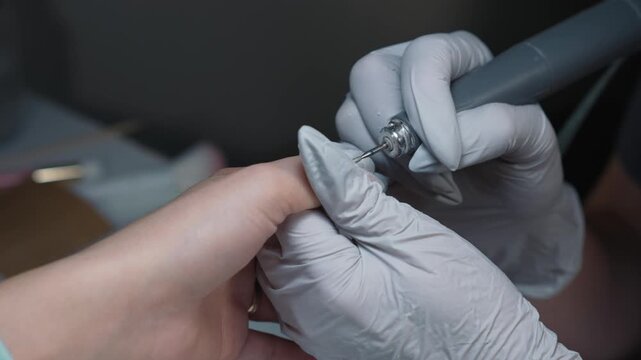 Professional electric leveling of nail plate in cuticle and nail tip area before polygel application in beauty salon