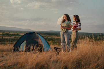 Fototapeta premium Friends camping outdoors at sunset enjoying nature