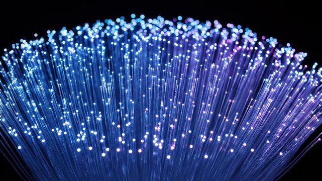 Close-up of illuminated fiber optic strands showcasing digital data flow and network connectivity on a dark background