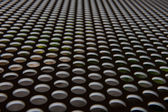 Perforated metal surface creating abstract pattern with holes