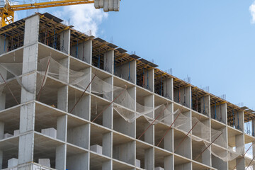 Construction of a modern building with a clear blue sky and cranes working on the upper levels in a bustling urban area © beholdereye