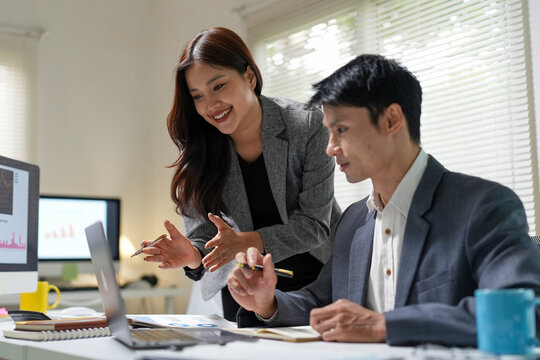 Business professionals collaborating and analyzing data during a team meeting using computer technology in an office setting for corporate strategy