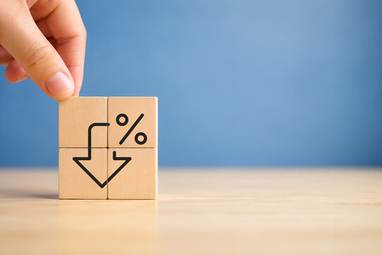 Financial decline and percentage decrease concept. Wooden blocks with downward arrow with a percentage sign, representing financial decline, economic downturn, decreasing interest rates, deflation.