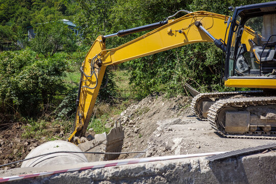 Excavator road construction drainage pipe installation civil engineering infrastructure, heavy machinery digging trench for utility works, earthworks and maintenance.