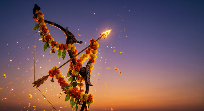 Traditional Indian bow and flaming arrow decorated with marigold flowers during a sunset festival celebration.