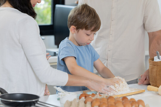 A child is mixing flour and dough with family