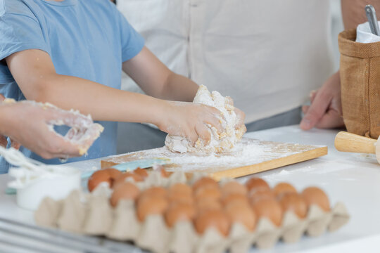 A child is mixing flour and dough with family
