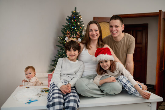 family with children cutting out paper Christmas tree ornaments in living room. A cozy weekend, time spent with the kids. lifestyle, live photos, real people