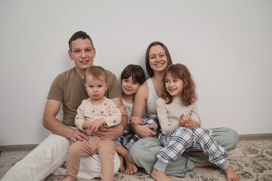 Family with children sitting on the floor in the living room, cozy weekend, time spent together with children