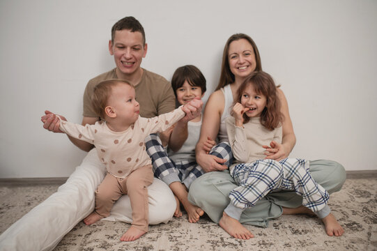 Family with children sitting on the floor in the living room, cozy weekend, time spent together with children
