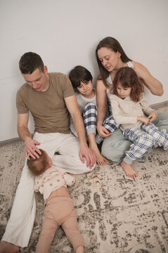 Family with children sitting on the floor in the living room, cozy weekend, time spent together with children