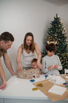 family with children cutting out paper Christmas tree ornaments in living room. A cozy weekend, time spent with the kids. Blurry, out-of-focus photos, background, lifestyle, live photos, real people