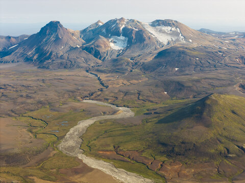 Aerial view of Kerlingarfjoll mountain range with volcanic peaks, glaciers, and a winding river in the rugged landscape of Hrunamannahreppur, Iceland.