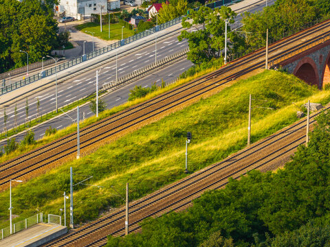 Aerial view of the historic railway viaduct in Olsztyn, featuring parallel train tracks, lush green embankments, and a nearby road in Olsztyn, Warmian-Masurian Voiv, Poland.