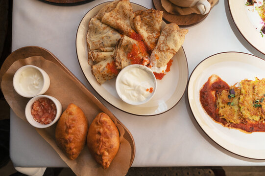 Thin crepes folded on a plate with red caviar and sour cream, served as traditional festive breakfast or appetizer.