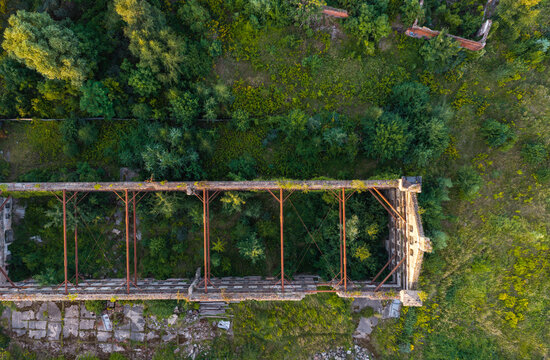 Aerial view of a ruined industrial building structure with exposed metal beams and lush green vegetation growing inside the walls in Gdansk, Pomeranian Voivodeship, Poland.