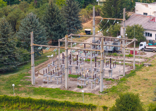 Aerial view of an electrical substation with metal structures, power lines, and insulators surrounded by green trees and grass in Ohrid, Municipality of Ohrid, North Macedonia.