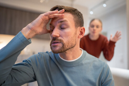 Annoyed man refusing listen to constantly complaining woman, married couple in relationships crisis, husband sitting on sofa ignoring frustrated wife, manipulative emotions, quarrel and arguments.