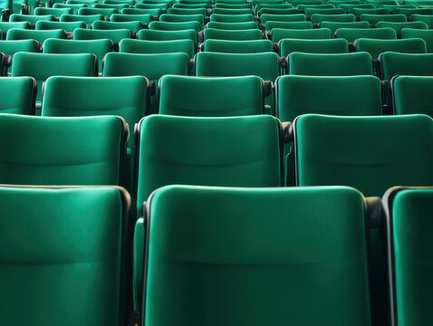 Rows of empty green cinema seats receding into the distance. Theatre auditorium, film screening, live performance and audience seating in entertainment venue