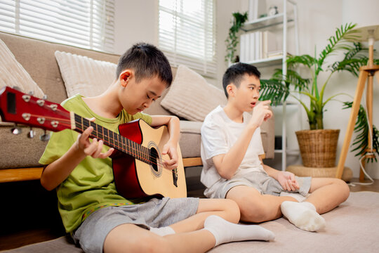 Two Brothers Playing Guitar Together at Home