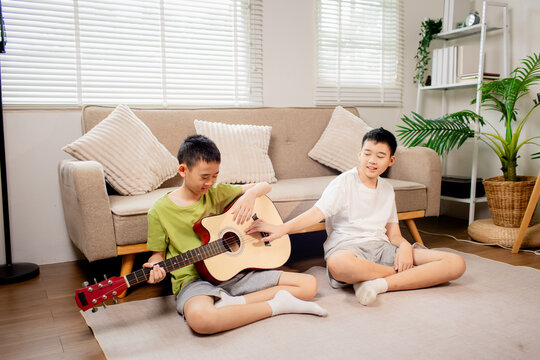 Two Brothers Playing Guitar Together at Home