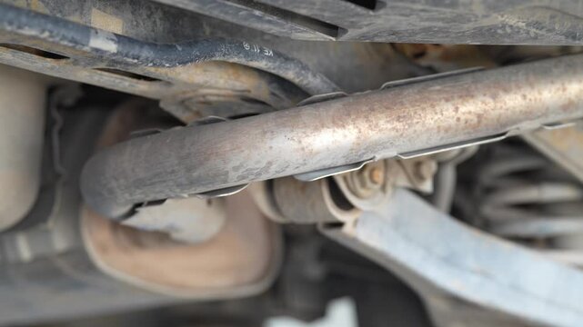Close up shot of car underbody exhaust pipe with muffler.