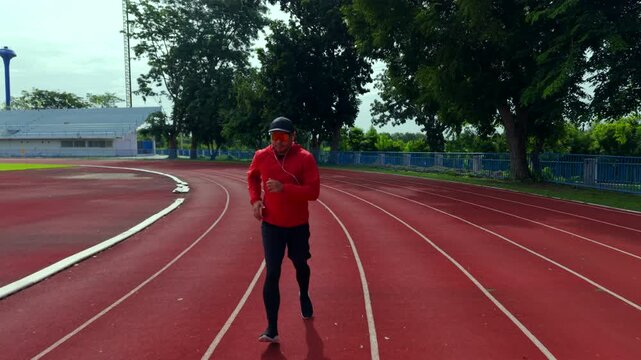Drone view of a man running on an outdoor stadium track while challenging himself to reach fitness goals. The scene represents motivation, personal achievement, healthy lifestyle and active wellness.
