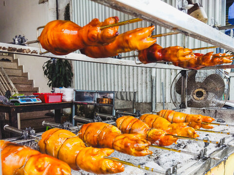 Roasted pig on a spit in a market with fans in the background  