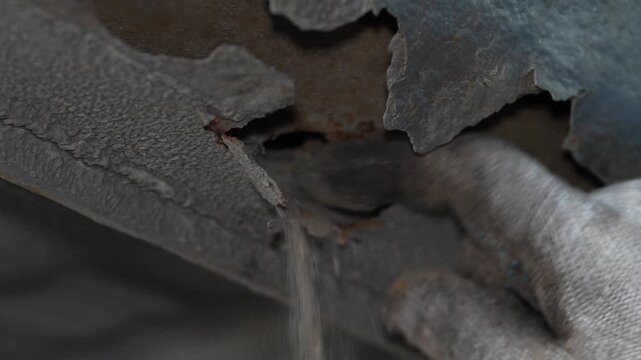Mechanic touching a heavily rusted car underbody with severe corrosion.