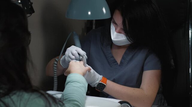 Manicure technician performs electric nail tip processing near cuticle area to improve polygel adhesion to nail plate
