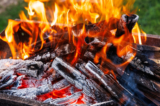 Hot glowing embers and fire flames in barbecue grill, charcoal wood burning and cooking concept