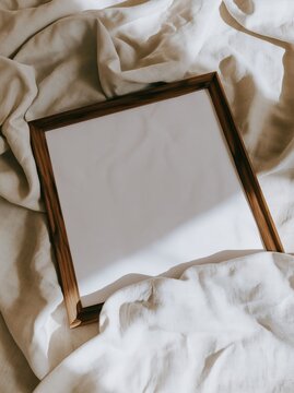 square wooden frame lies on light, soft fabric. sunlight shines on fabric, creating warm and inviting atmosphere in quiet indoor setting