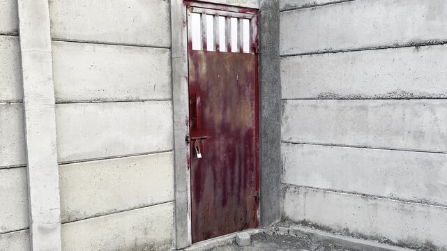 Old rusty metal door on weathered concrete boundary wall