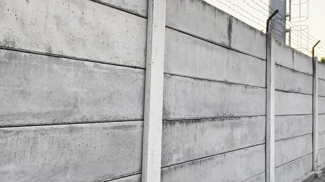 High concrete boundary wall with barbed wire fence