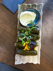 Dolma - Traditional Dish of Georgian Cuisine - Stuffed Grape Leaves with Meat served with Sauce Decorated with Flowers on a Plate. Top View. © troyka